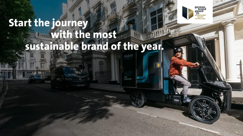 Electric cargo vehicle parked on a residential city street lined with elegant townhouses.