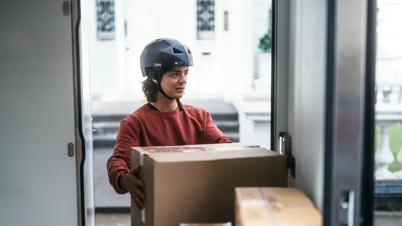 Delivery worker loading parcels into a cargo vehicle for urban deliveries